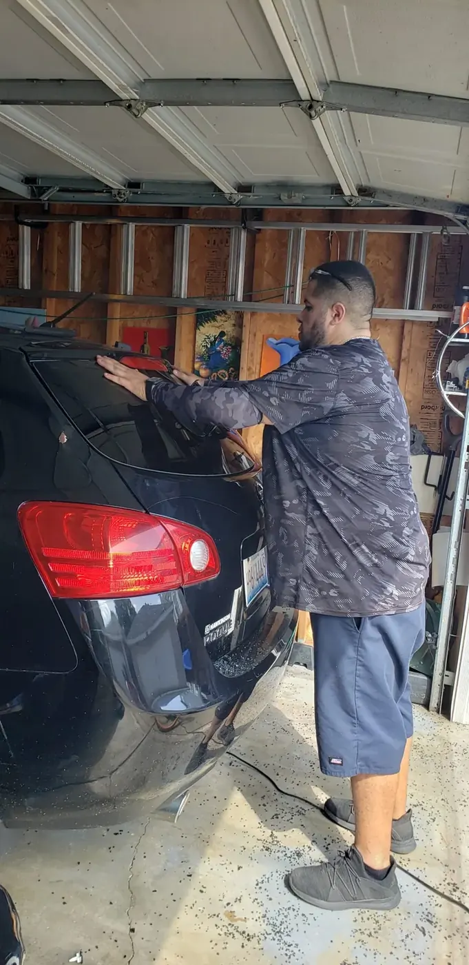 Technician tinting a red car side window