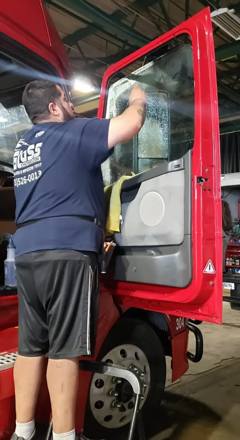 Technician applying window tint film to a truck window
